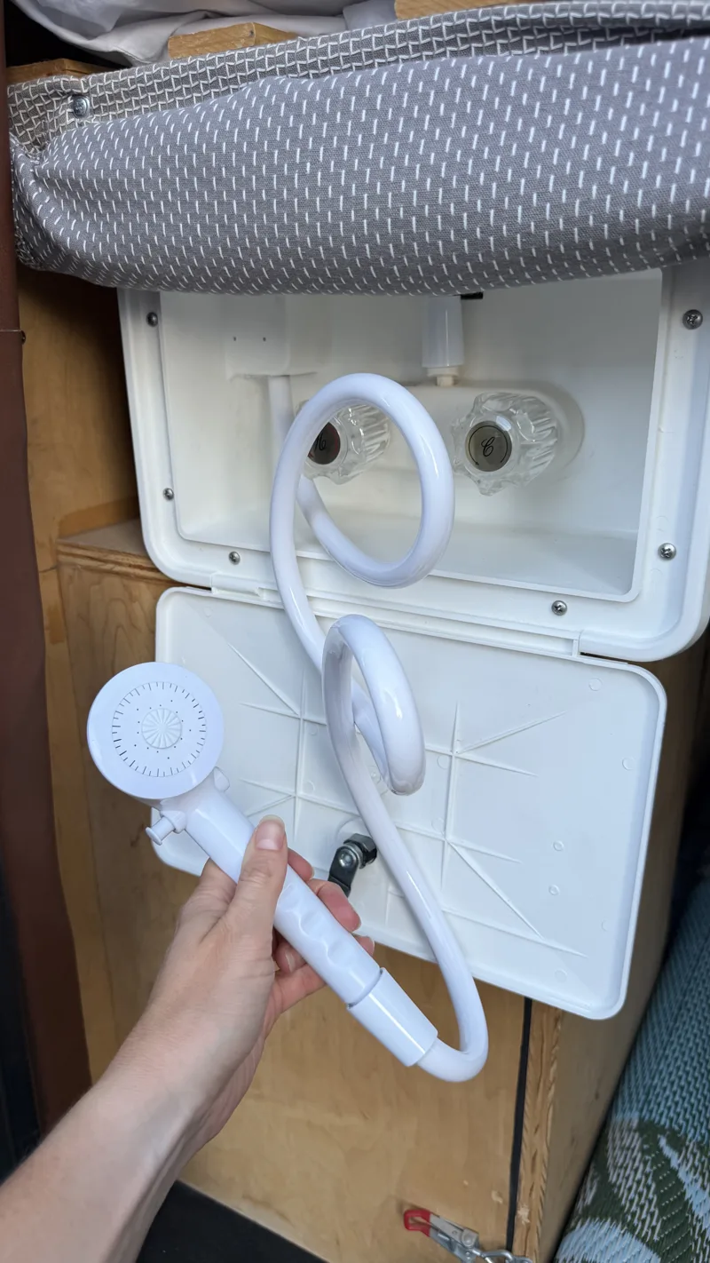 Outdoor shower hose and sprayer in their storage compartment