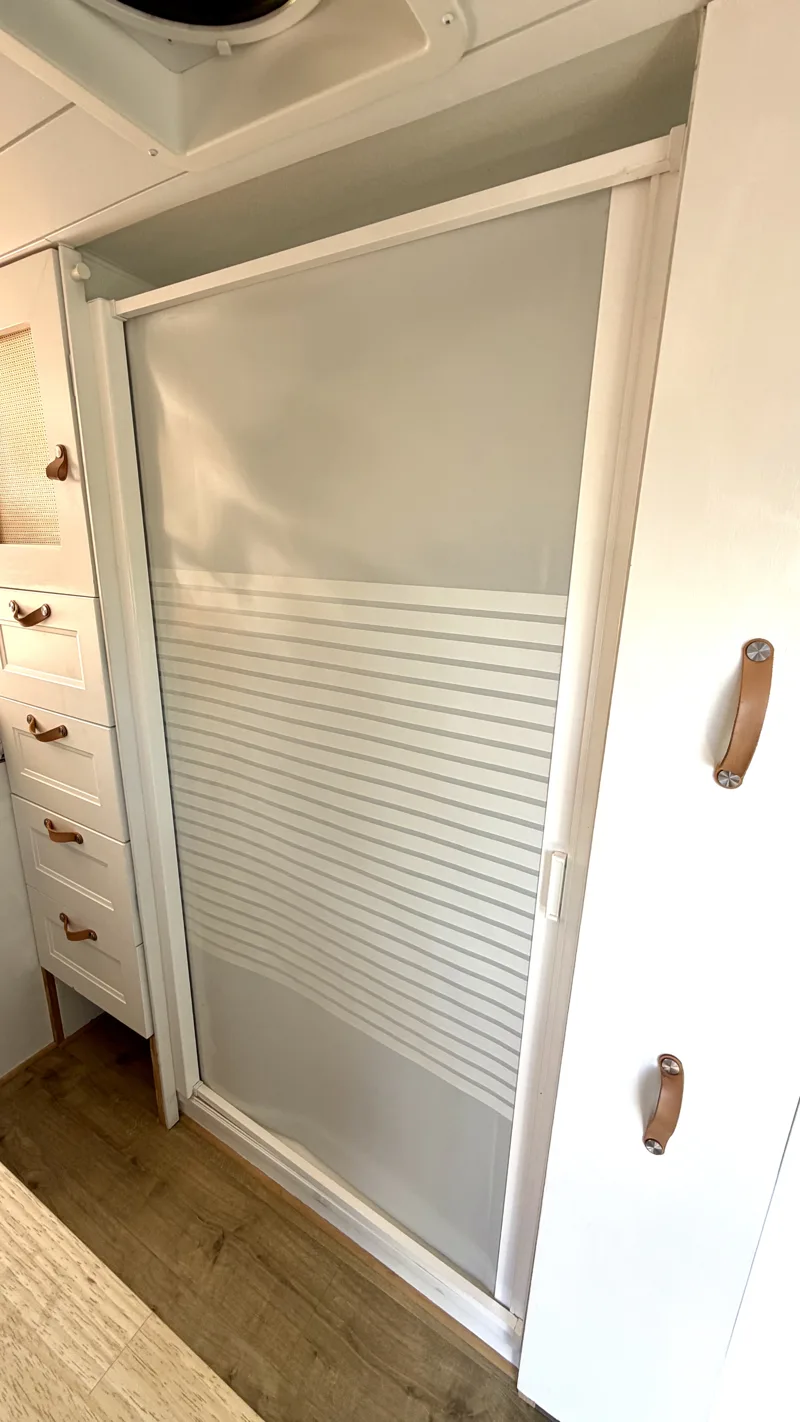 Closed shower door beside the kitchen pantry