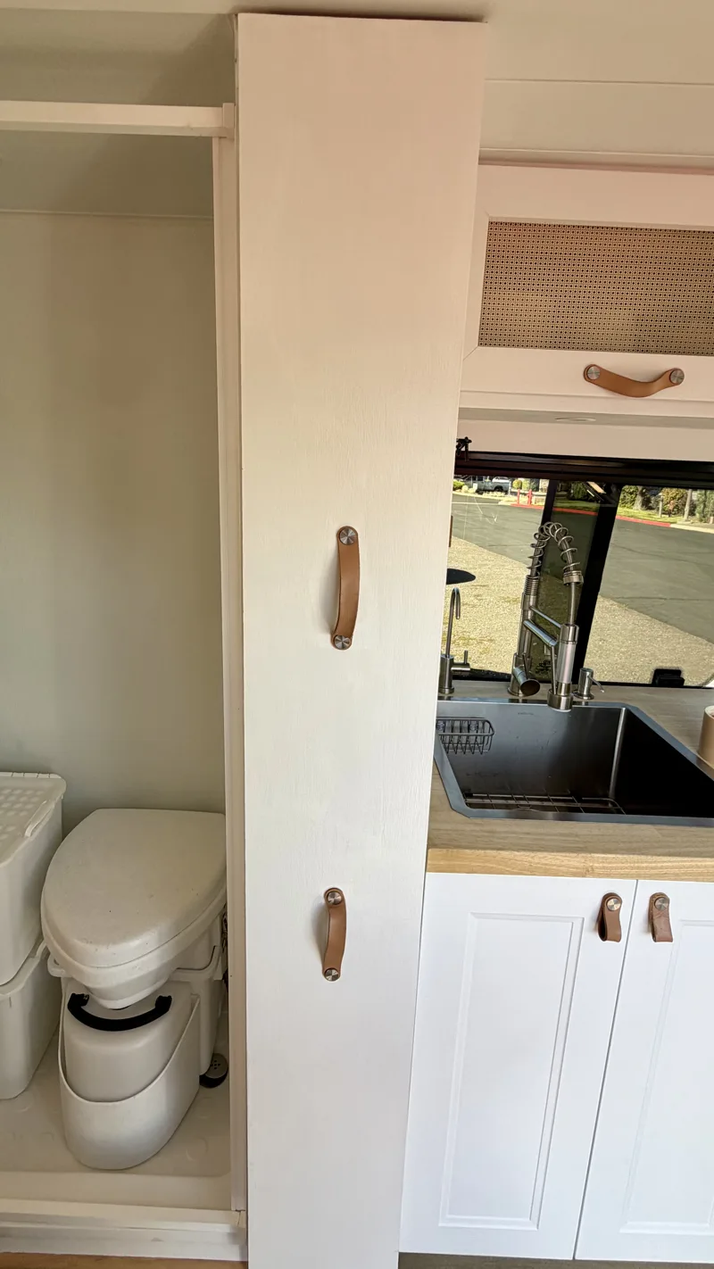Tall pantry cabinet with the door closed beside the bathroom