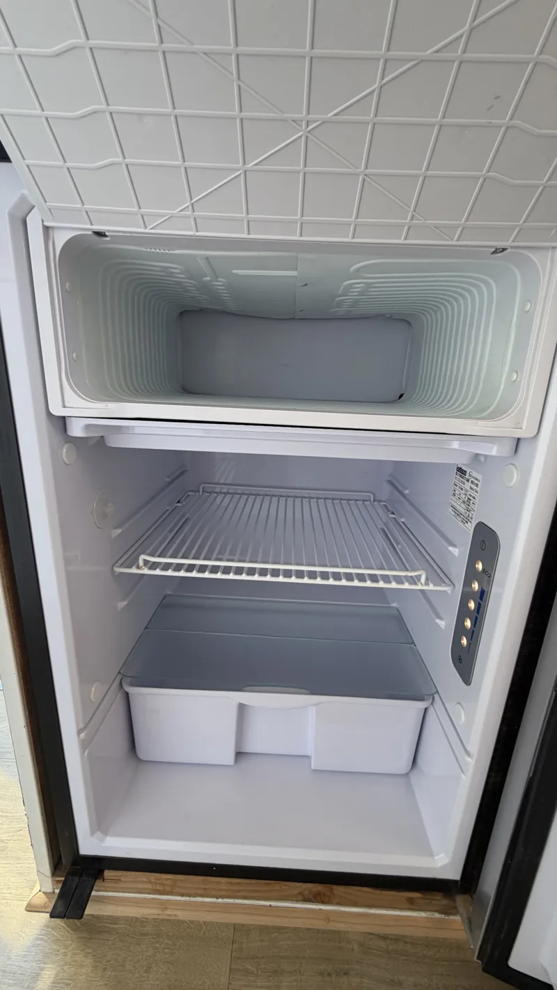 Inside Pebbles’ refrigerator showing the freezer compartment, shelves, and lower drawer