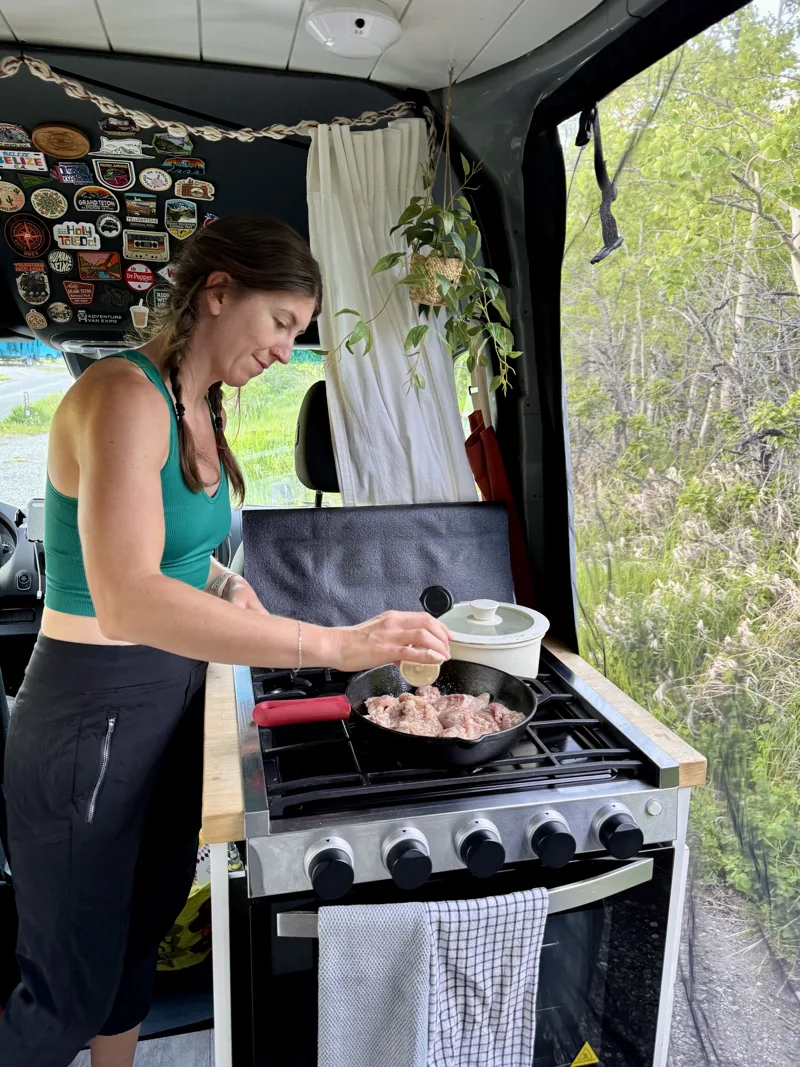 Steph cooking at the stove beside the open sliding door
