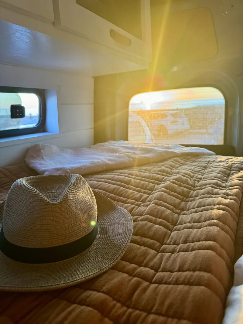 Sunlight falling across the bed and a hat