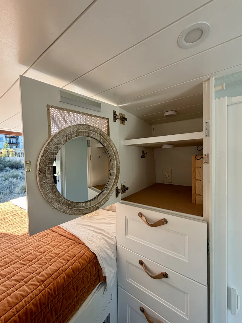 Vanity cabinet open with a round mirror on the door
